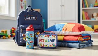 Close-up of neatly arranged children’s personalised everyday essentials—water bottle, embroidered backpack, lunch box, bedding, and folded clothing—in a bright room setting.